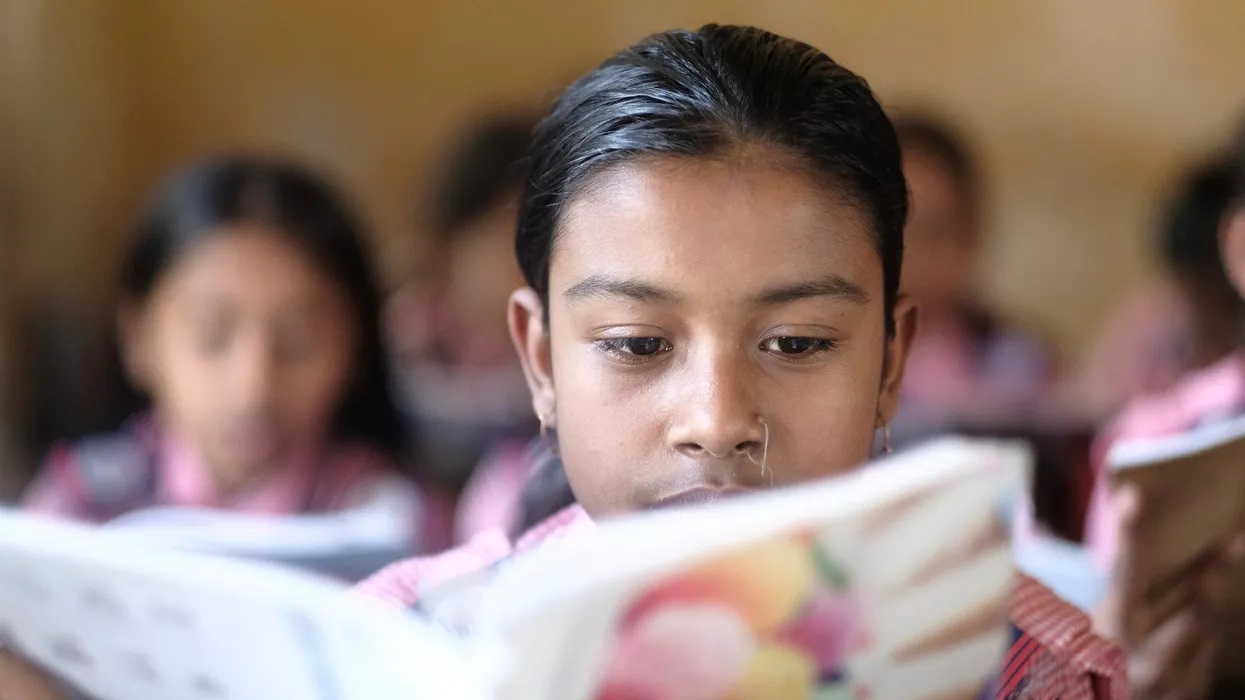 Portrait Of Smiling Girl Reading Book At School In Dhaka Bangladesh